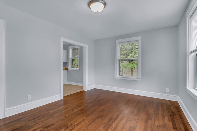unfurnished room with plenty of natural light, baseboards, and wood finished floors