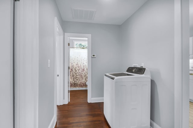 clothes washing area featuring washer / clothes dryer, dark wood-style flooring, and baseboards