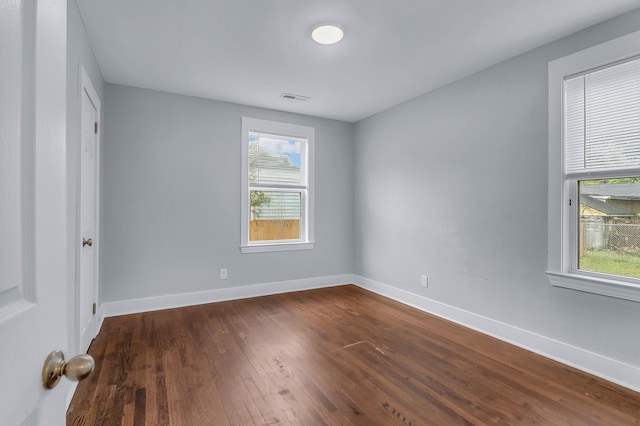 unfurnished room featuring plenty of natural light, dark wood-style flooring, and baseboards