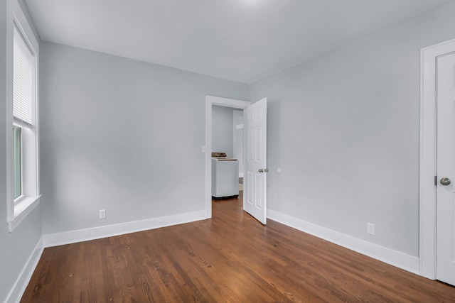 empty room featuring washer / clothes dryer, dark wood-type flooring, and baseboards