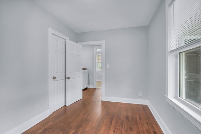 unfurnished bedroom featuring baseboards, washer / clothes dryer, and dark wood-type flooring
