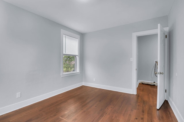 empty room featuring dark wood-style floors and baseboards