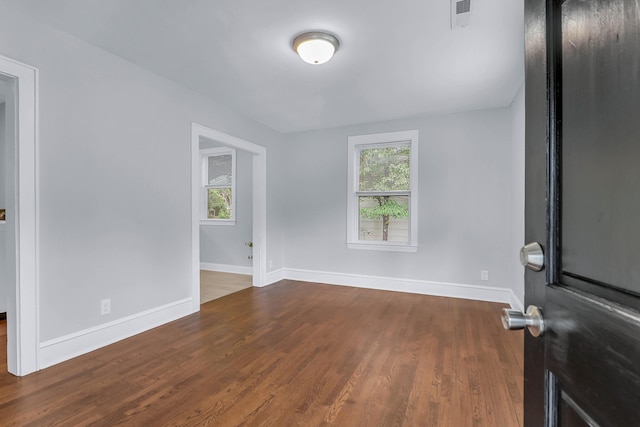 spare room with plenty of natural light, wood finished floors, and baseboards