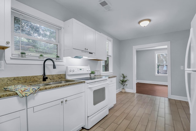 kitchen featuring white appliances, under cabinet range hood, a sink, white cabinetry, and plenty of natural light