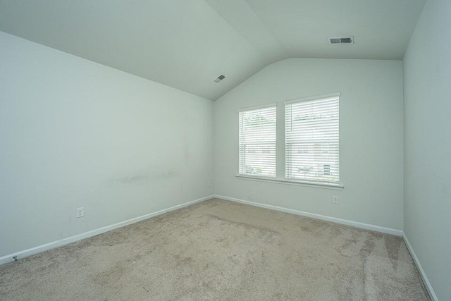 unfurnished room featuring light colored carpet and vaulted ceiling