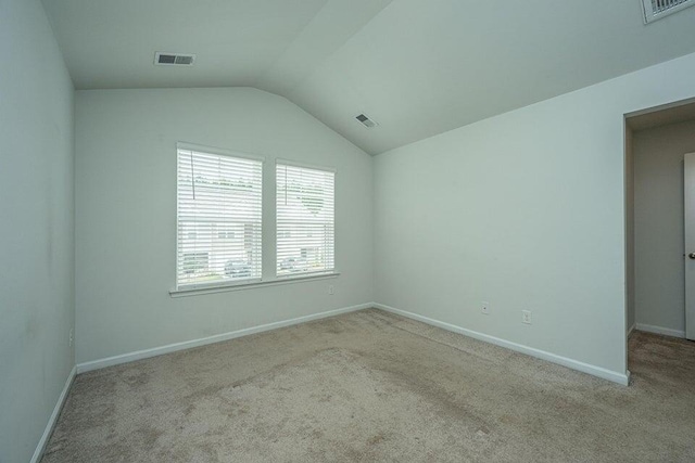 carpeted empty room featuring vaulted ceiling