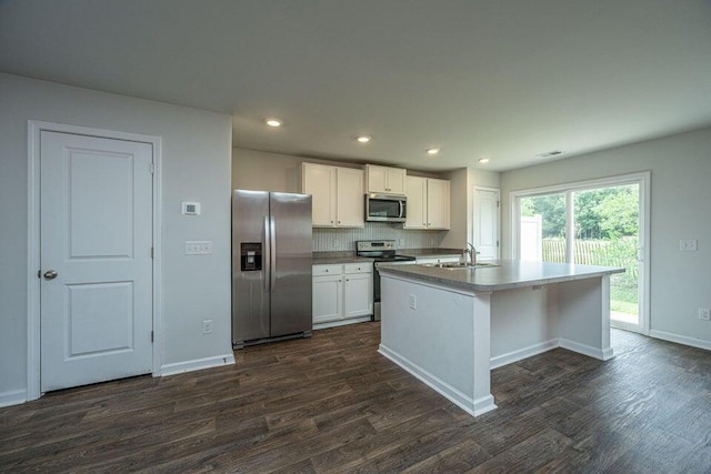 kitchen featuring backsplash, white cabinets, sink, an island with sink, and stainless steel appliances