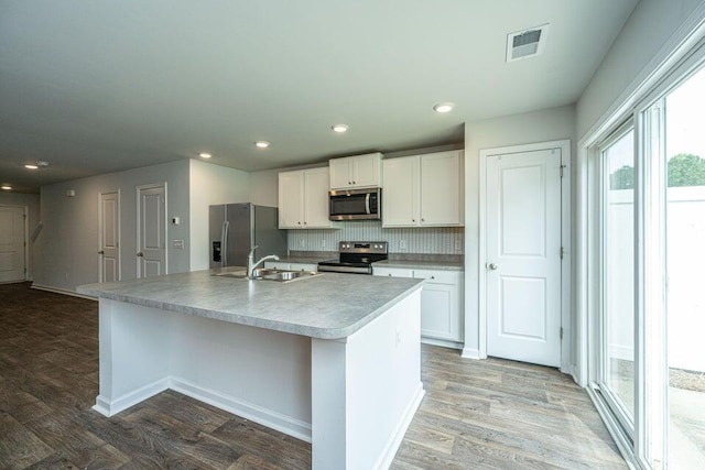 kitchen with white cabinetry, sink, a kitchen island with sink, appliances with stainless steel finishes, and hardwood / wood-style flooring