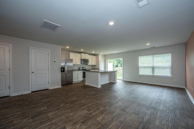 kitchen with a center island, stainless steel appliances, white cabinetry, and dark wood-type flooring