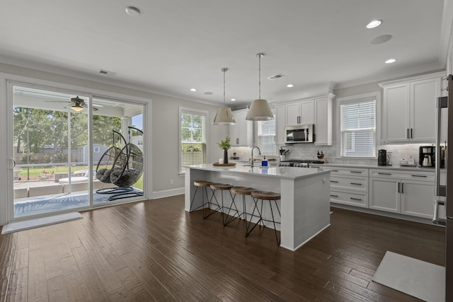 4019 Cascades Thrust, Summerville, SC 29483 - kitchen with stainless steel microwave, crown molding, white cabinetry, decorative backsplash, and light countertops