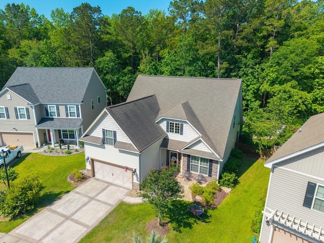 view of front of home with a front lawn, roof with shingles, driveway, and stone siding