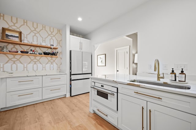kitchen with open shelves, a sink, light stone counters, white cabinets, and white appliances