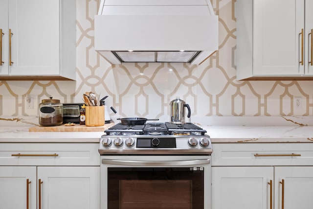 kitchen featuring light stone counters, white cabinets, custom range hood, and stainless steel gas stove