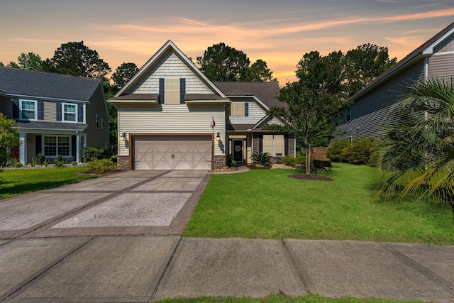 view of front of home with a yard, an attached garage, driveway, and stone siding