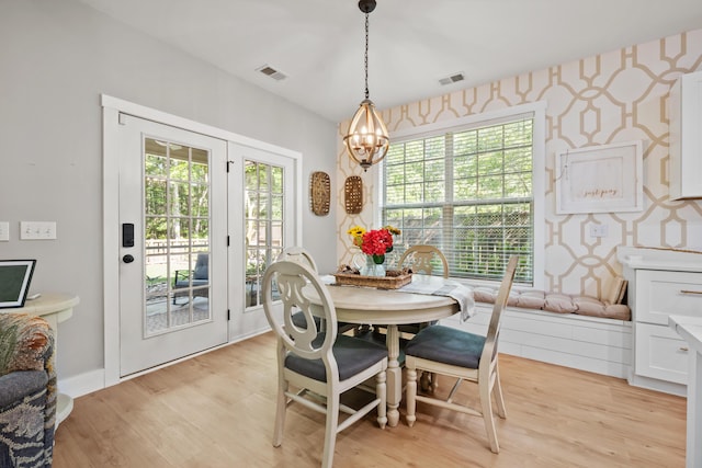 dining room featuring visible vents, light wood finished floors, and an inviting chandelier
