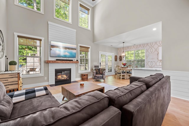 living room with a high ceiling, a fireplace with flush hearth, wood finished floors, and a chandelier