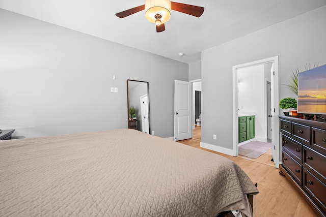 bedroom with a ceiling fan, ensuite bath, and light wood-style floors