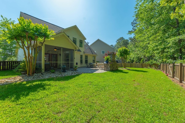 view of yard with a sunroom, ceiling fan, a fenced backyard, and a patio area