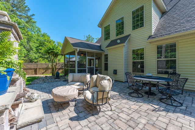 view of patio with a sunroom, outdoor dining area, fence, and an outdoor living space