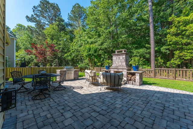 view of patio featuring an outdoor stone fireplace, a fenced backyard, outdoor dining space, and a grill