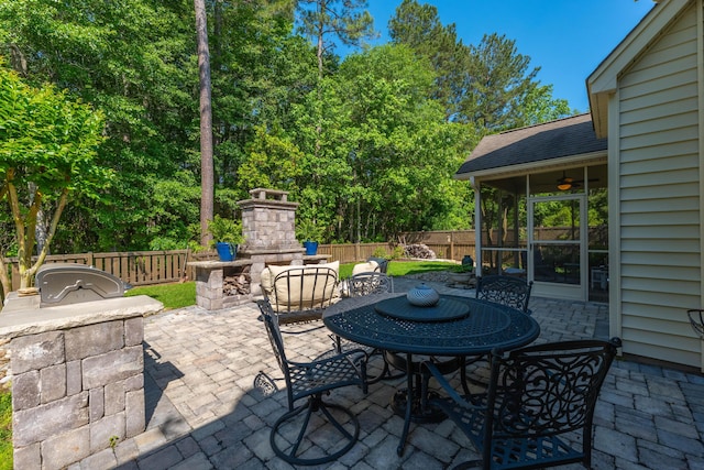 view of patio / terrace featuring an outdoor stone fireplace, fence, and a ceiling fan