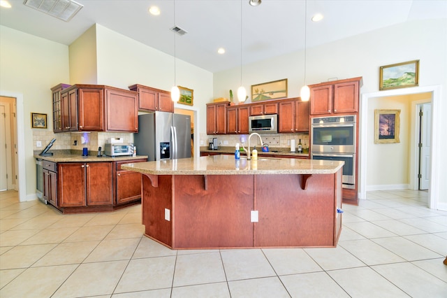 kitchen featuring light tile patterned floors, stainless steel appliances, a breakfast bar, a high ceiling, and visible vents