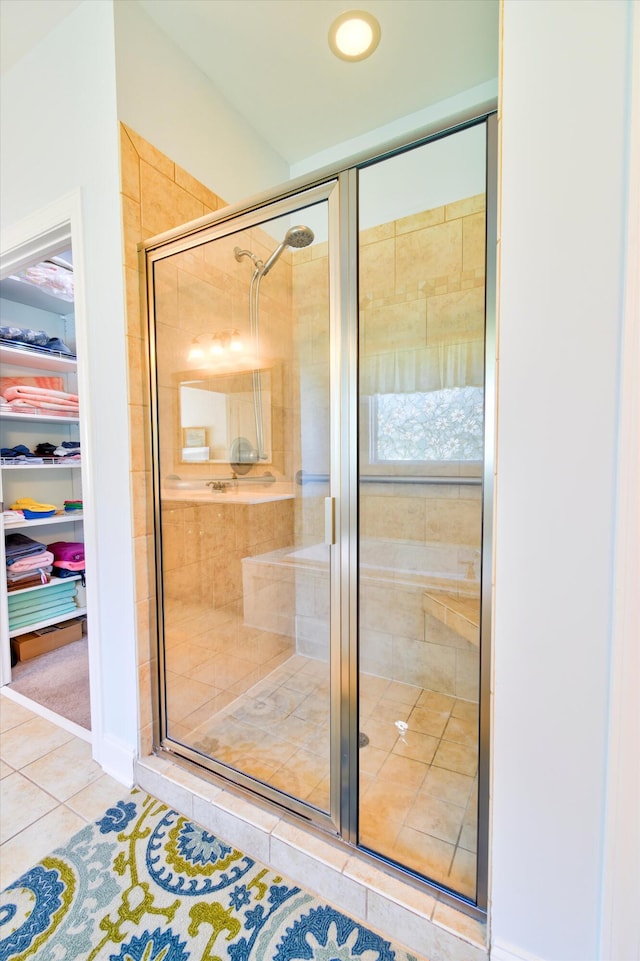 full bathroom featuring tile patterned flooring, a walk in closet, and a stall shower