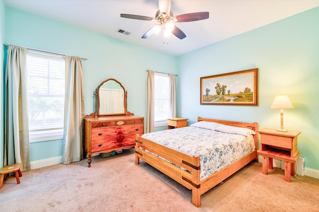 bedroom with light carpet, multiple windows, visible vents, and baseboards