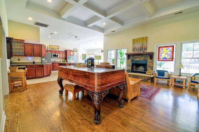 dining area featuring a towering ceiling, beam ceiling, light wood-style floors, and coffered ceiling