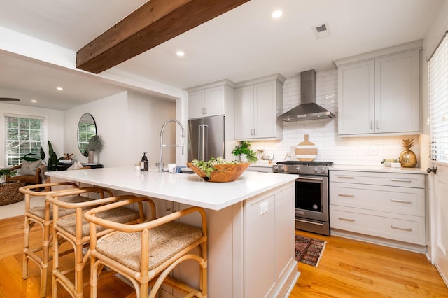 31 Lyttleton Ave, Charleston, SC 29407 - kitchen with appliances with stainless steel finishes, wall chimney exhaust hood, a kitchen breakfast bar, decorative backsplash, and light wood-type flooring