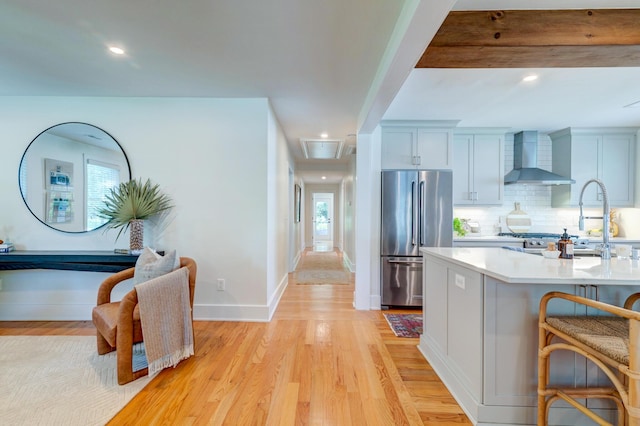 31 Lyttleton Ave, Charleston, SC 29407 - kitchen with high end refrigerator, wall chimney exhaust hood, light countertops, a breakfast bar, and light wood-type flooring