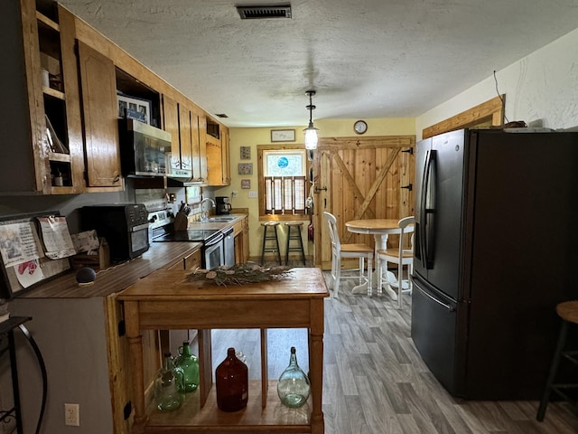 kitchen featuring visible vents, dark wood-type flooring, stainless steel appliances, a textured ceiling, and a sink