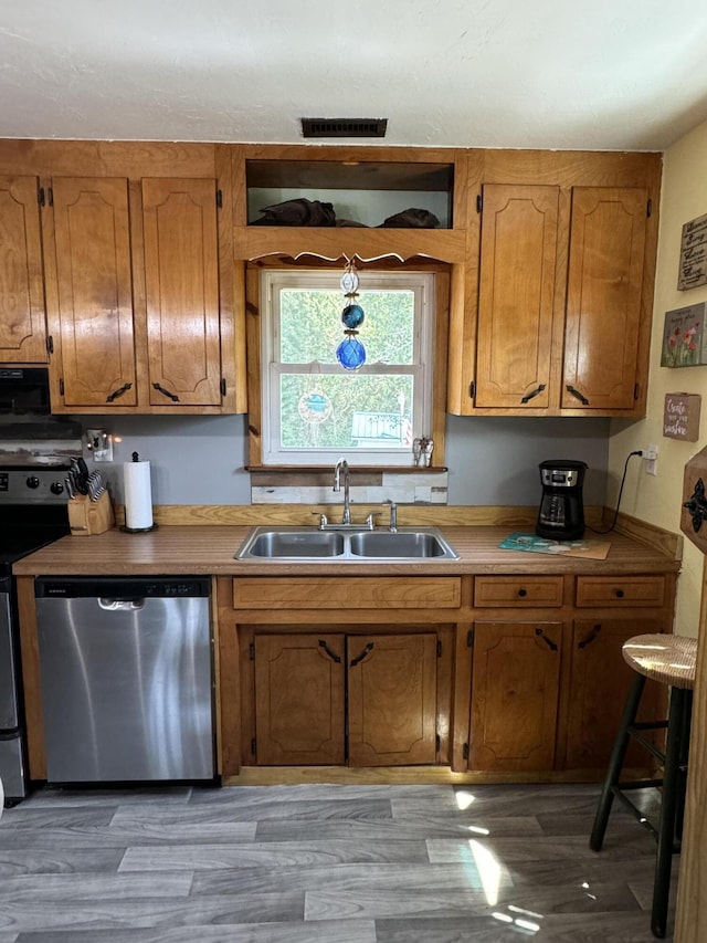 kitchen with dishwasher, brown cabinets, wood finished floors, electric range, and a sink