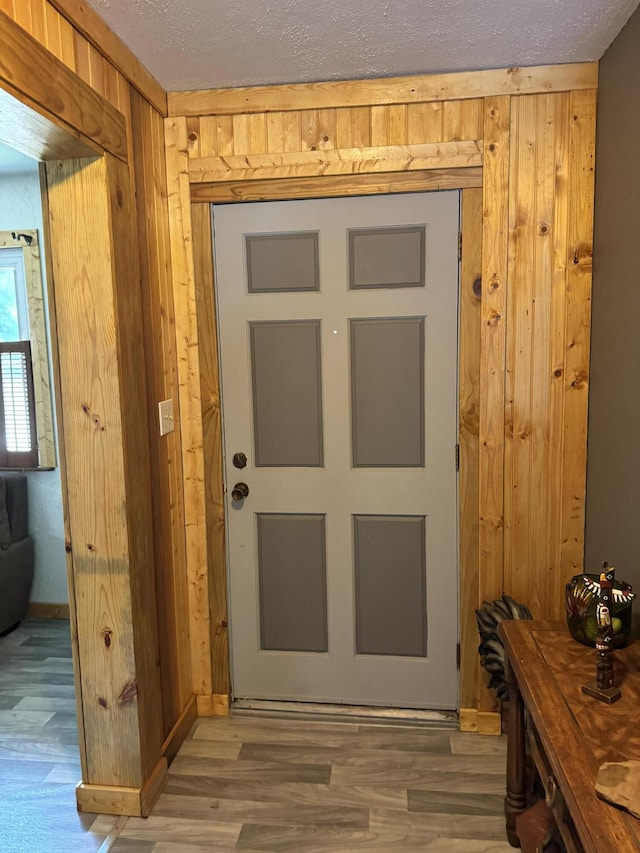 interior space with wood finished floors, a textured ceiling, and wood walls