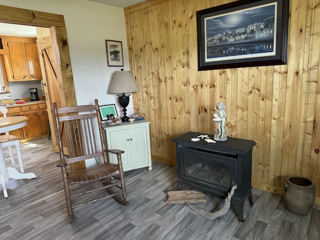 living area with a wood stove, wood finished floors, baseboards, and wood walls