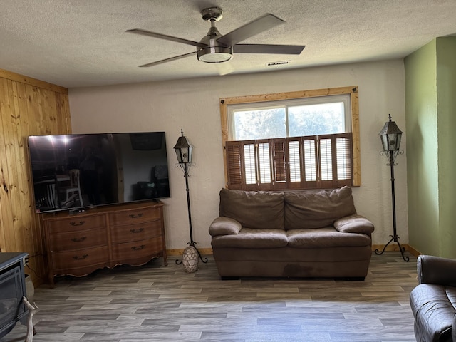 living area with visible vents, a textured ceiling, ceiling fan, and wood finished floors