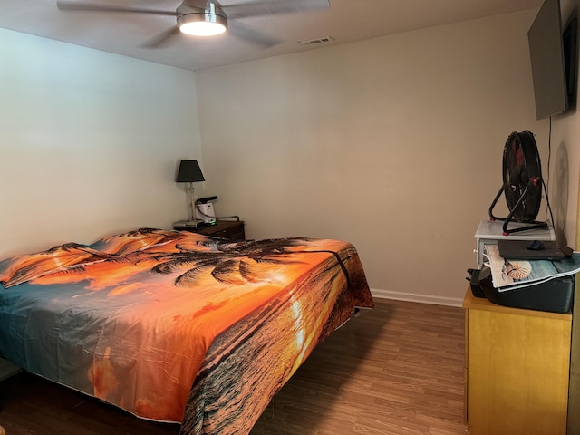 bedroom featuring visible vents, ceiling fan, baseboards, and wood finished floors