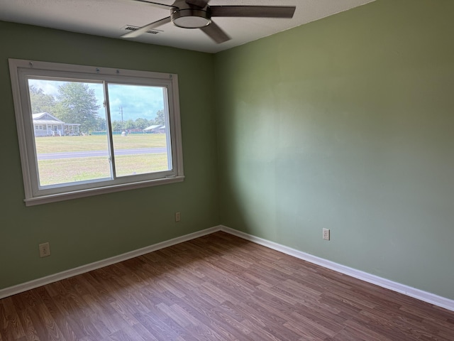 empty room with visible vents, a ceiling fan, baseboards, and wood finished floors