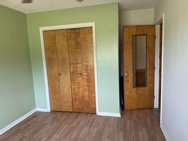 unfurnished bedroom with wood finished floors, baseboards, a closet, and a textured ceiling