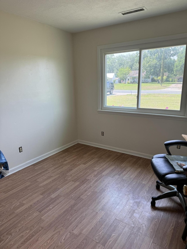 interior space with visible vents, baseboards, a textured ceiling, and wood finished floors