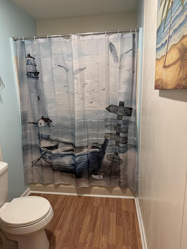 full bathroom featuring curtained shower, toilet, and wood finished floors