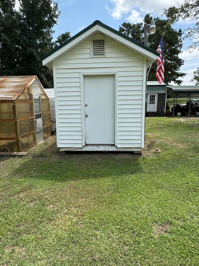 view of greenhouse with a storage shed and a yard