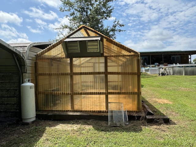 view of greenhouse featuring an outdoor pool and a yard