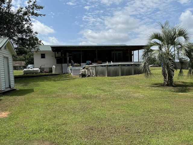 rear view of house featuring a lawn, an outdoor pool, and metal roof