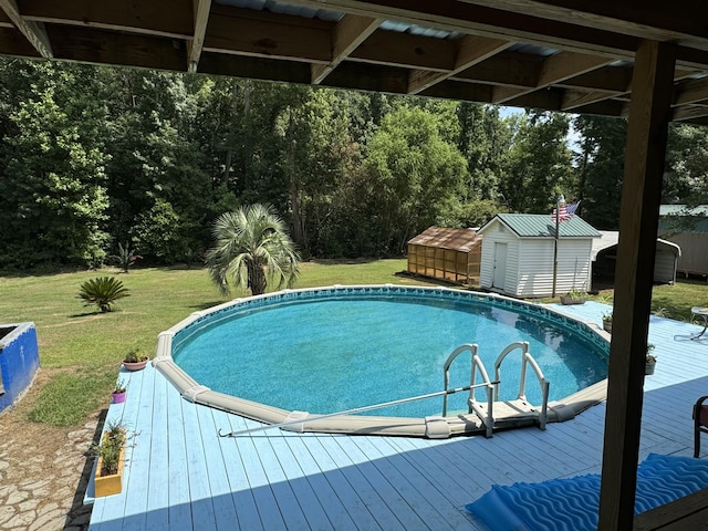 view of pool featuring a storage unit, an outbuilding, a wooden deck, and a yard