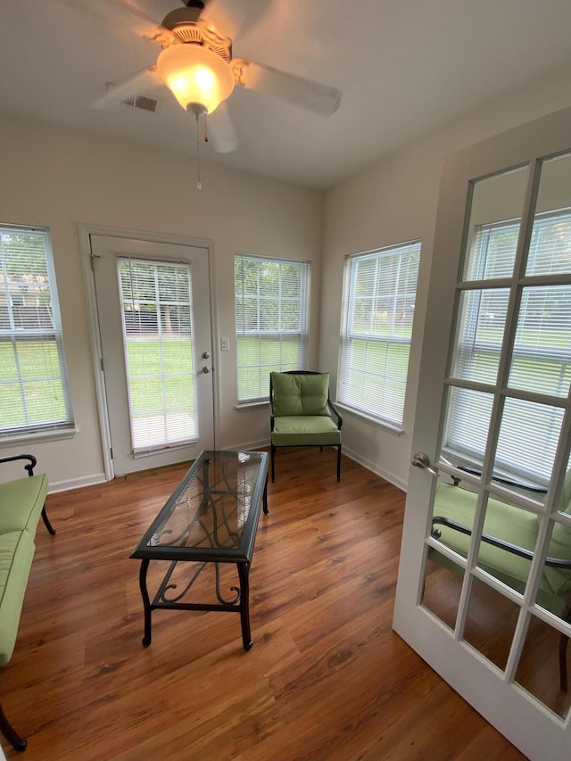 living area with wood finished floors, a ceiling fan, visible vents, and baseboards