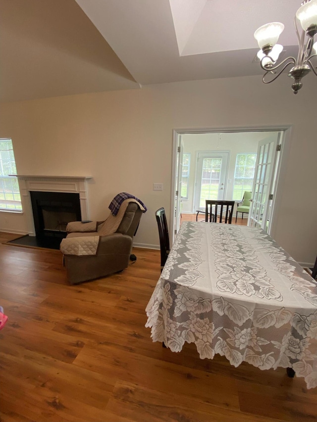 dining space featuring a wealth of natural light, wood finished floors, an inviting chandelier, and vaulted ceiling