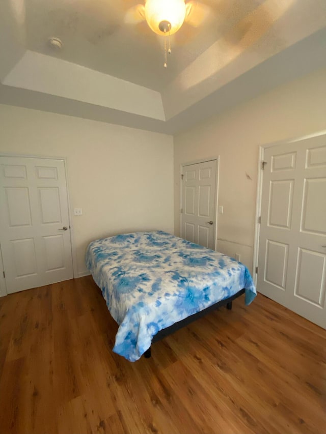 bedroom featuring ceiling fan, a raised ceiling, and hardwood / wood-style floors