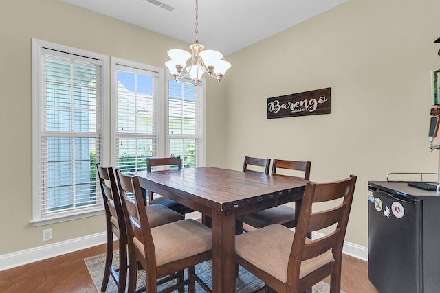 dining room with an inviting chandelier, baseboards, wood finished floors, and a healthy amount of sunlight