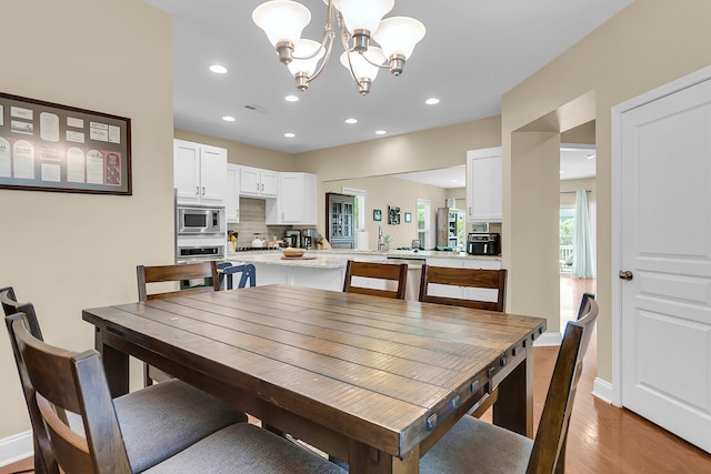 dining room with visible vents, light wood-type flooring, baseboards, an inviting chandelier, and recessed lighting